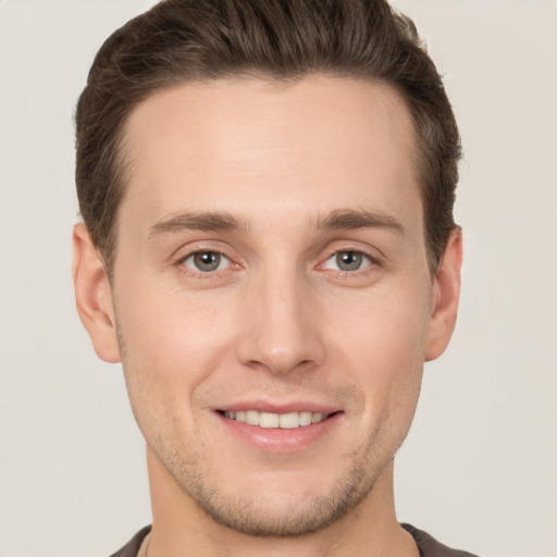 Joyful white young-adult male with short  brown hair and grey eyes