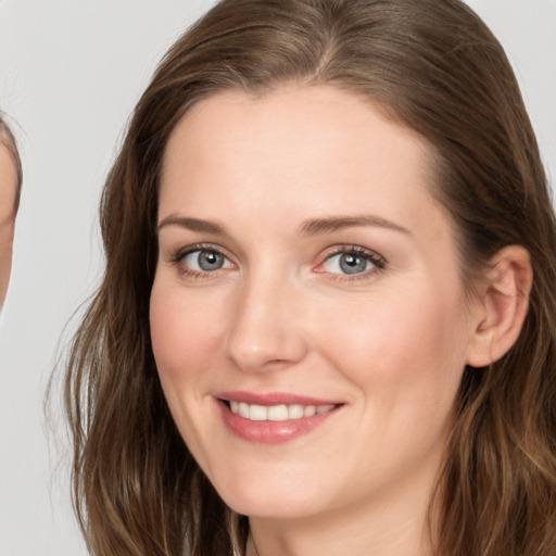 Joyful white young-adult female with long  brown hair and grey eyes