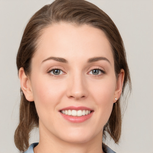 Joyful white young-adult female with medium  brown hair and grey eyes