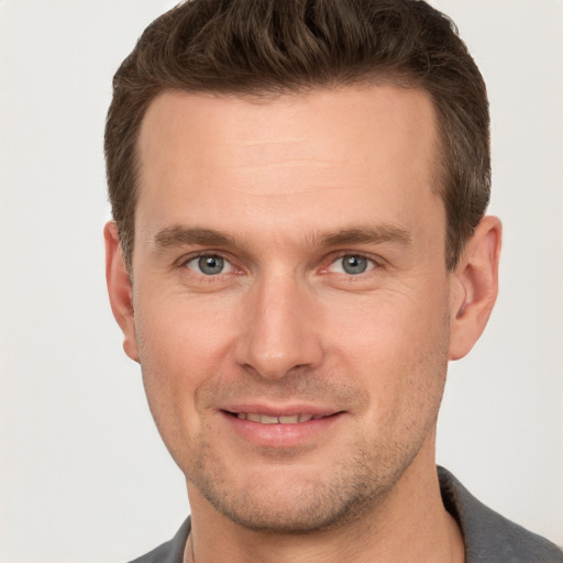 Joyful white young-adult male with short  brown hair and grey eyes