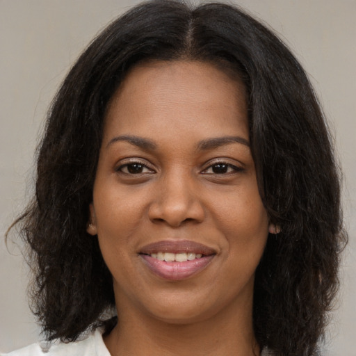 Joyful black young-adult female with long  brown hair and brown eyes