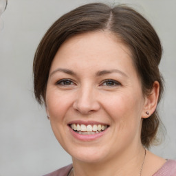 Joyful white young-adult female with medium  brown hair and grey eyes