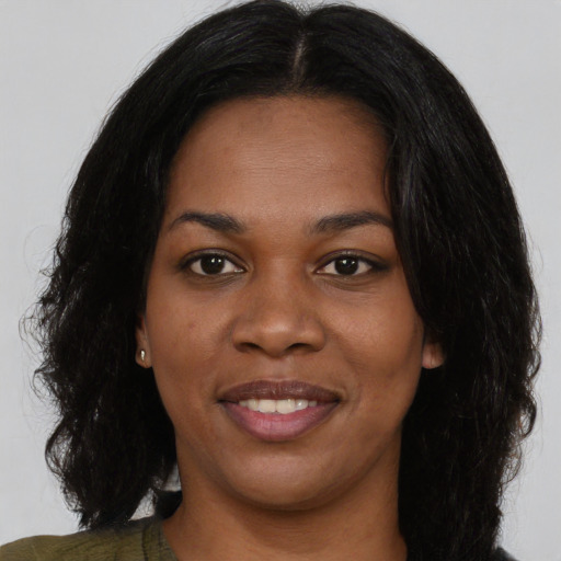 Joyful black young-adult female with long  black hair and brown eyes
