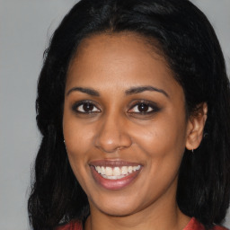 Joyful black young-adult female with long  brown hair and brown eyes