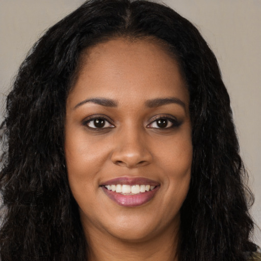 Joyful black young-adult female with long  black hair and brown eyes