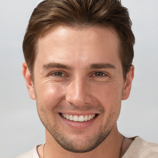 Joyful white young-adult male with short  brown hair and grey eyes