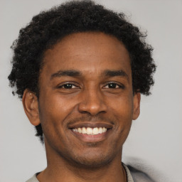 Joyful black young-adult male with short  brown hair and brown eyes