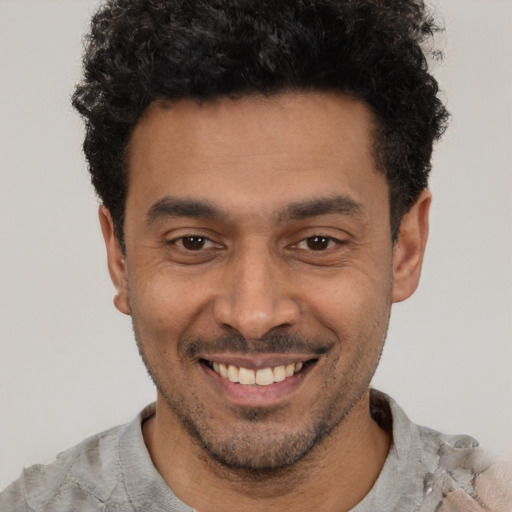 Joyful latino young-adult male with short  black hair and brown eyes