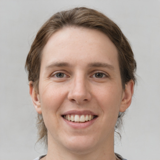 Joyful white young-adult female with medium  brown hair and grey eyes