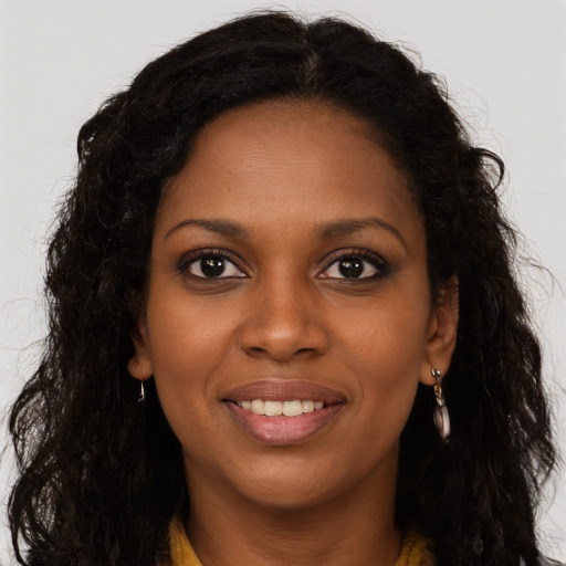 Joyful black young-adult female with long  brown hair and brown eyes