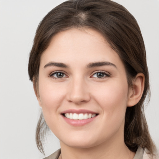 Joyful white young-adult female with medium  brown hair and grey eyes