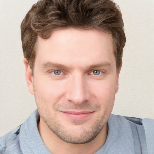 Joyful white young-adult male with short  brown hair and blue eyes