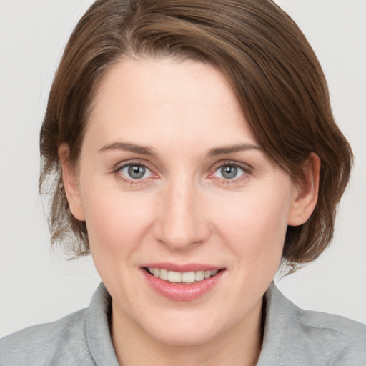 Joyful white young-adult female with medium  brown hair and grey eyes