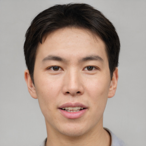 Joyful asian young-adult male with short  brown hair and brown eyes
