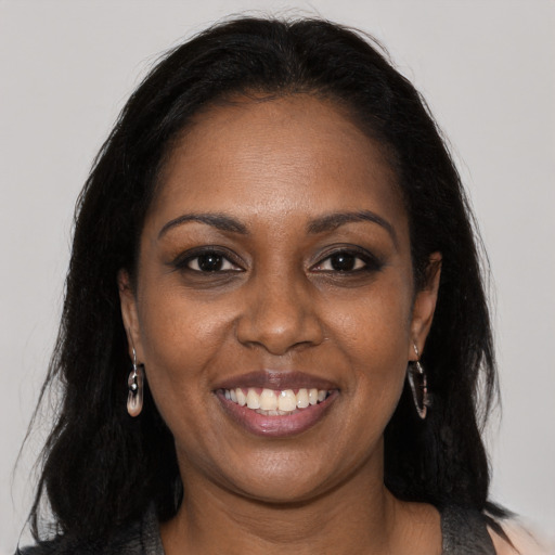 Joyful black young-adult female with long  brown hair and brown eyes