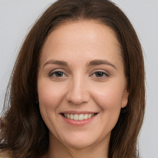 Joyful white young-adult female with long  brown hair and brown eyes