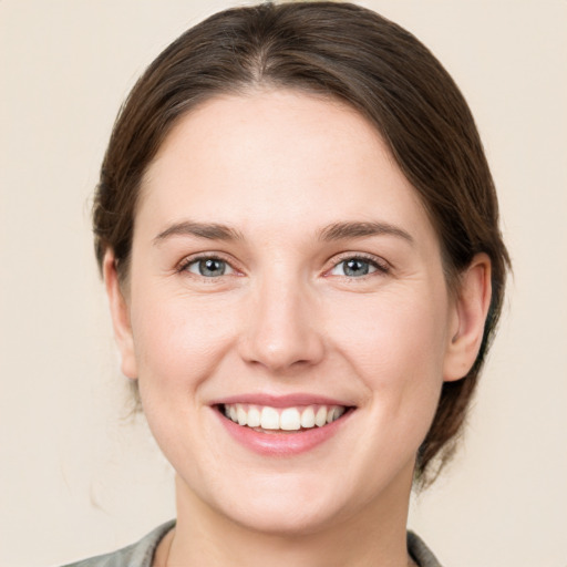 Joyful white young-adult female with medium  brown hair and grey eyes