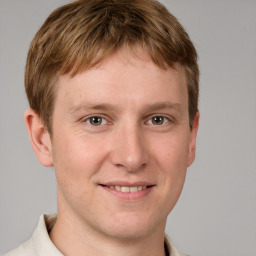 Joyful white young-adult male with short  brown hair and grey eyes