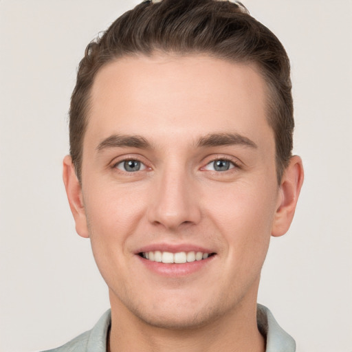 Joyful white young-adult male with short  brown hair and grey eyes