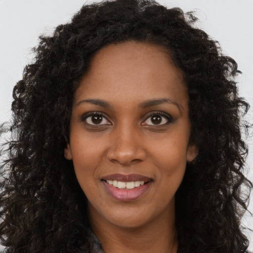 Joyful black young-adult female with long  brown hair and brown eyes