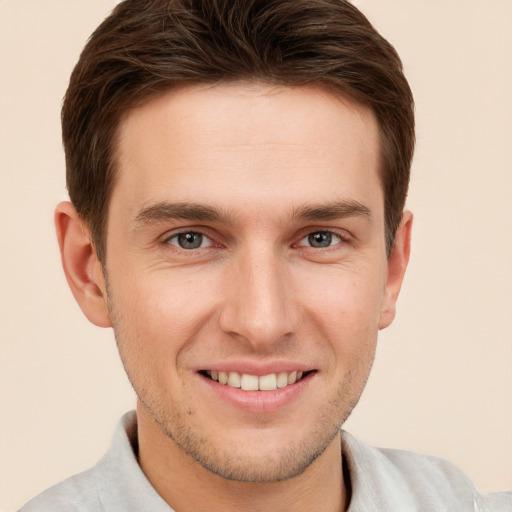 Joyful white young-adult male with short  brown hair and grey eyes