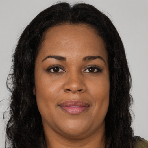 Joyful black young-adult female with long  brown hair and brown eyes