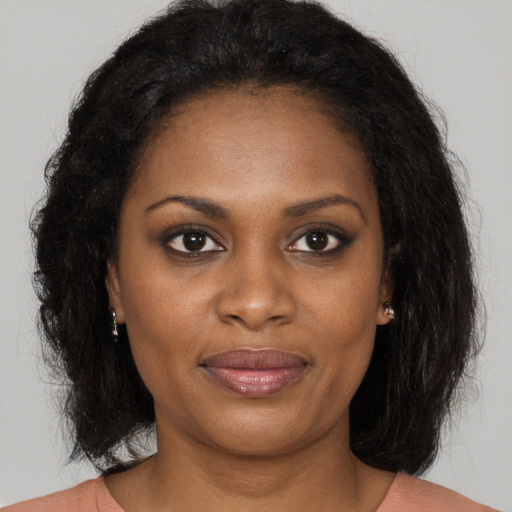 Joyful black young-adult female with long  brown hair and brown eyes