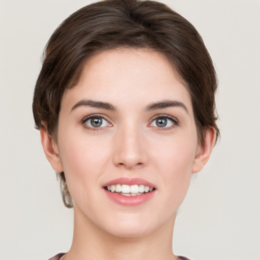 Joyful white young-adult female with short  brown hair and green eyes