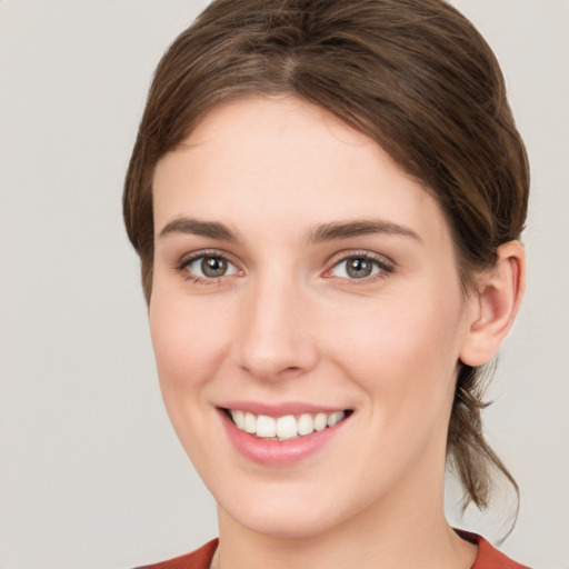 Joyful white young-adult female with medium  brown hair and grey eyes