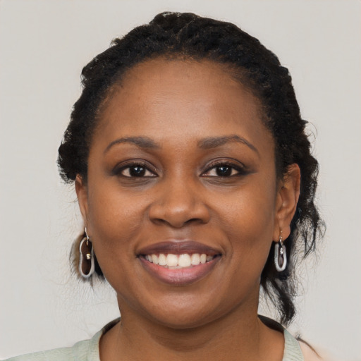 Joyful black young-adult female with short  black hair and brown eyes