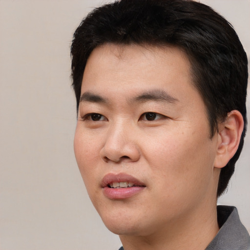Joyful asian young-adult male with short  black hair and brown eyes