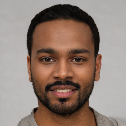 Joyful black young-adult male with short  black hair and brown eyes