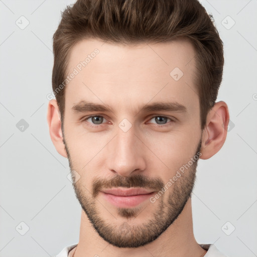 Joyful white young-adult male with short  brown hair and grey eyes