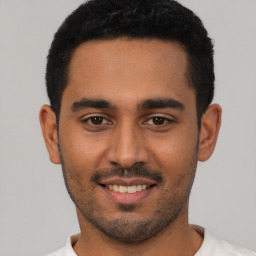 Joyful latino young-adult male with short  black hair and brown eyes