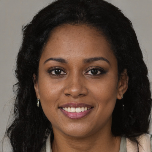 Joyful black young-adult female with long  brown hair and brown eyes