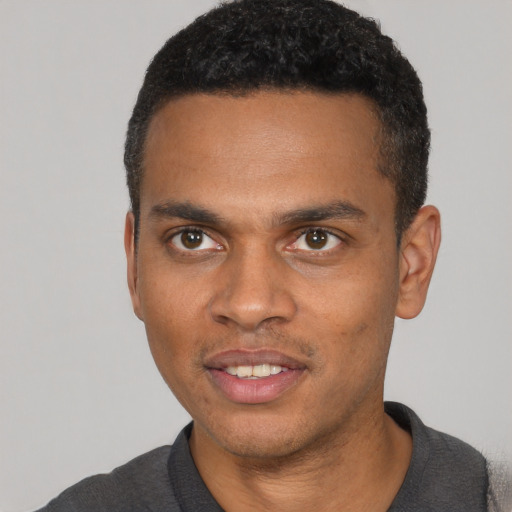 Joyful black young-adult male with short  black hair and brown eyes