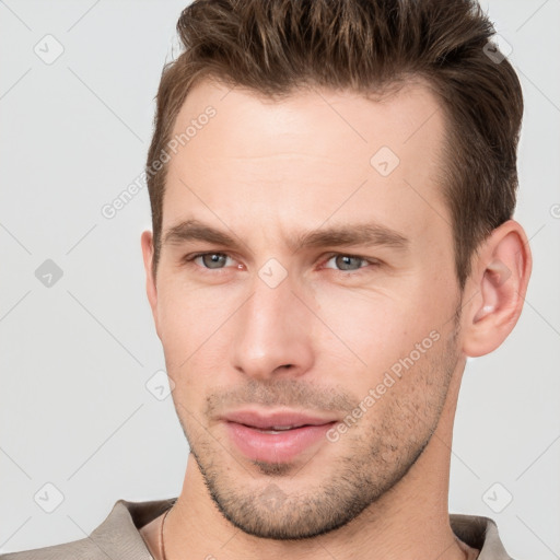 Joyful white young-adult male with short  brown hair and grey eyes