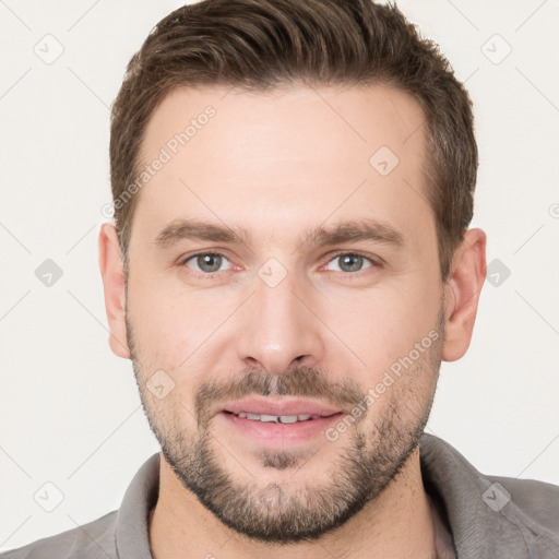 Joyful white young-adult male with short  brown hair and grey eyes