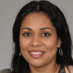 Joyful black young-adult female with long  brown hair and brown eyes