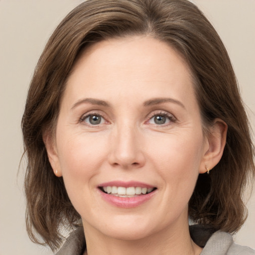 Joyful white adult female with medium  brown hair and grey eyes