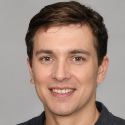 Joyful white young-adult male with short  brown hair and grey eyes