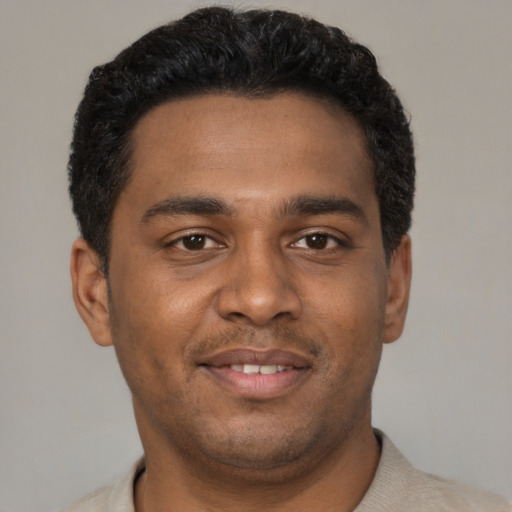 Joyful black young-adult male with short  black hair and brown eyes