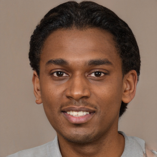 Joyful black young-adult male with short  black hair and brown eyes