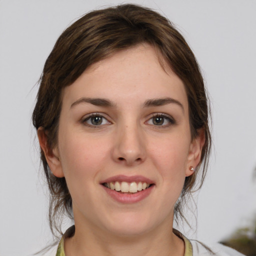 Joyful white young-adult female with medium  brown hair and grey eyes