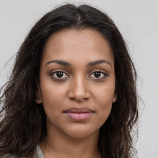 Joyful black young-adult female with long  brown hair and brown eyes