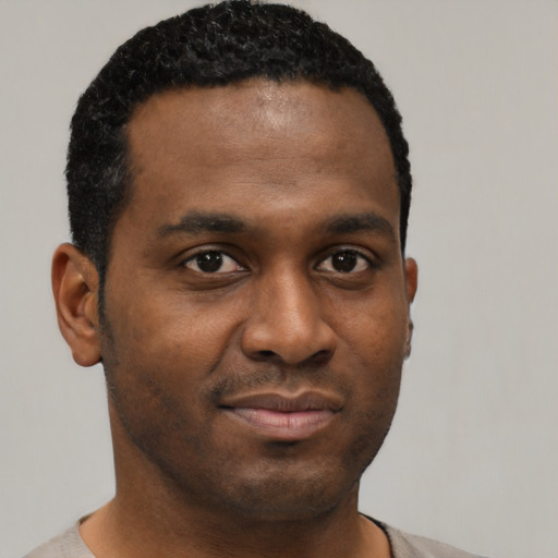 Joyful black young-adult male with short  brown hair and brown eyes