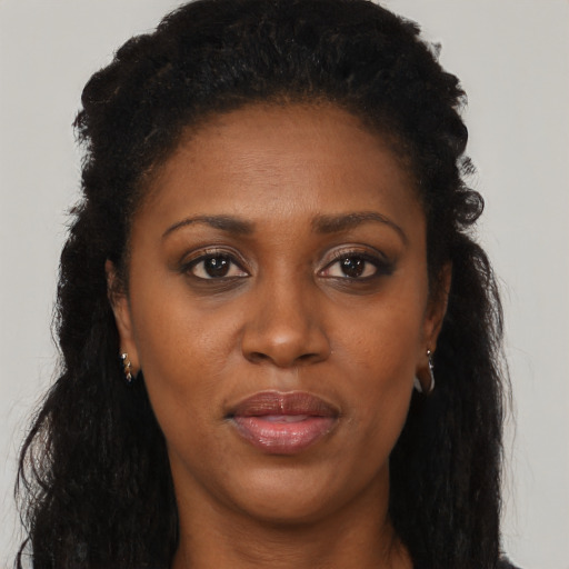 Joyful black adult female with long  brown hair and brown eyes