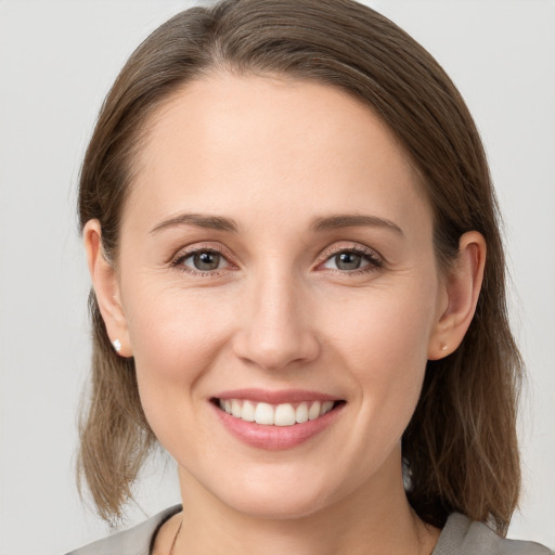 Joyful white young-adult female with medium  brown hair and grey eyes