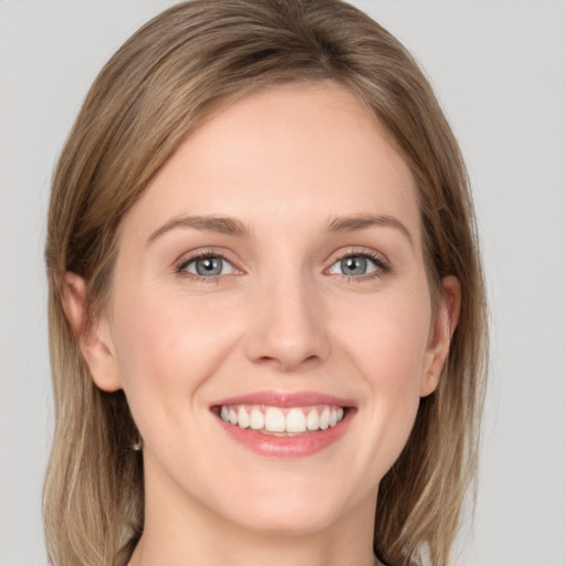 Joyful white young-adult female with medium  brown hair and grey eyes