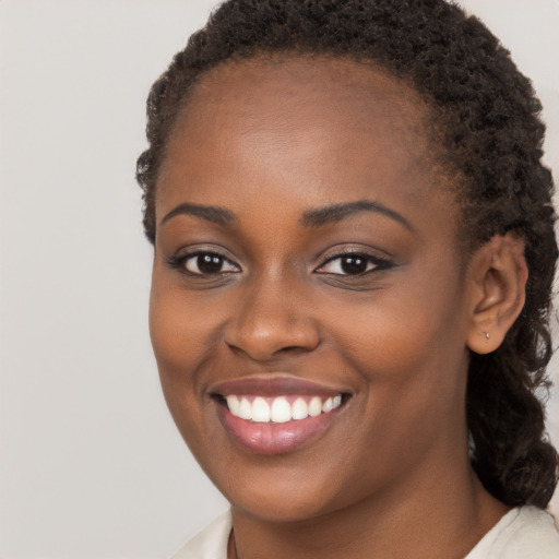 Joyful black young-adult female with long  brown hair and brown eyes